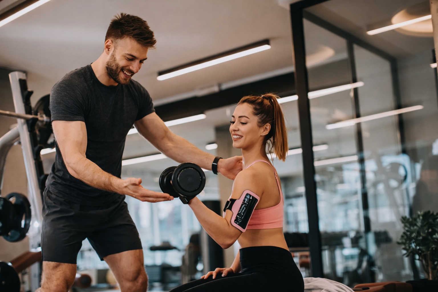 Trainer betreut eine Kundin beim Hanteltraining im Studio