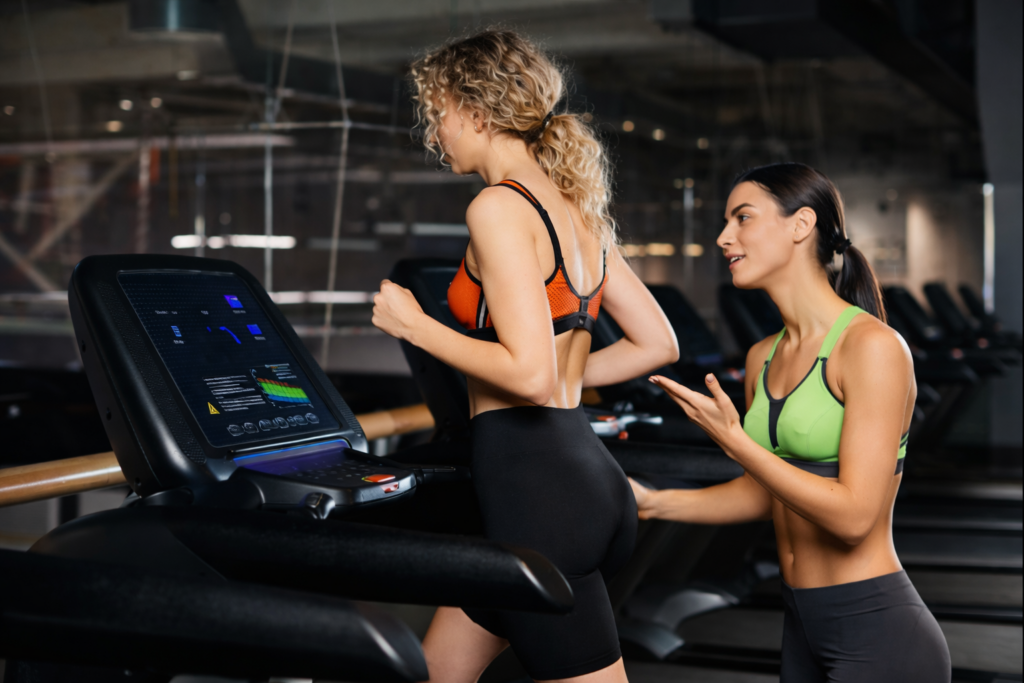 Personal trainer guiding treadmill workout